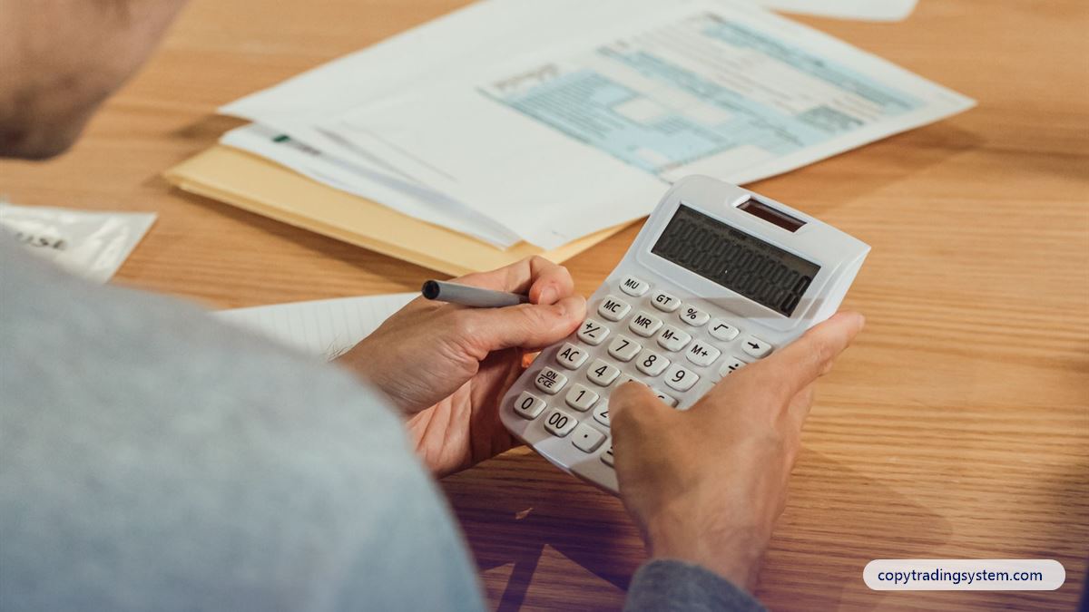 Copy trading fees: a person using a calculator with financial documents