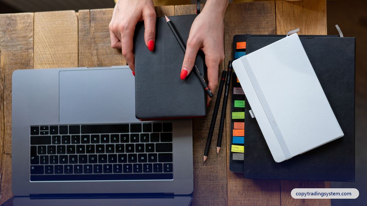 How to start copy trading: a laptop, planner and notebooks on a desk